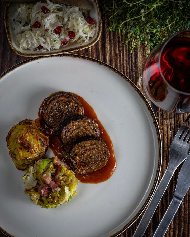 wagyu-roulade, Rinderrouladen, Wirsingrouladen, Rindsrouladen, Rinderroulade, Fleischrouladen serviert mit Beilage auf einem weißen Teller